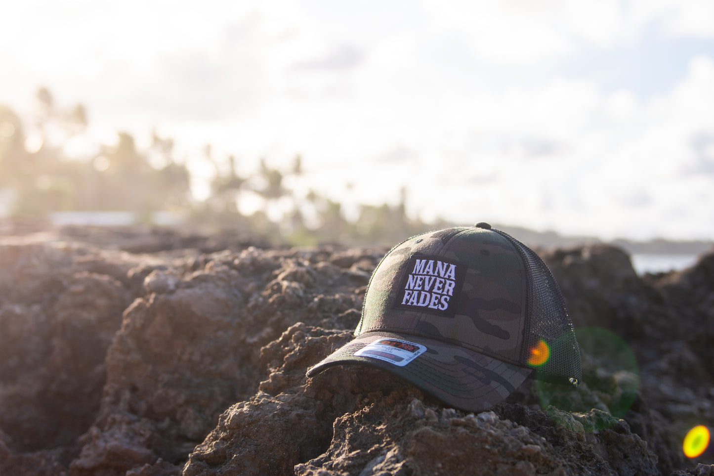 Black cap with 'Mana Never Fades' text on a field background